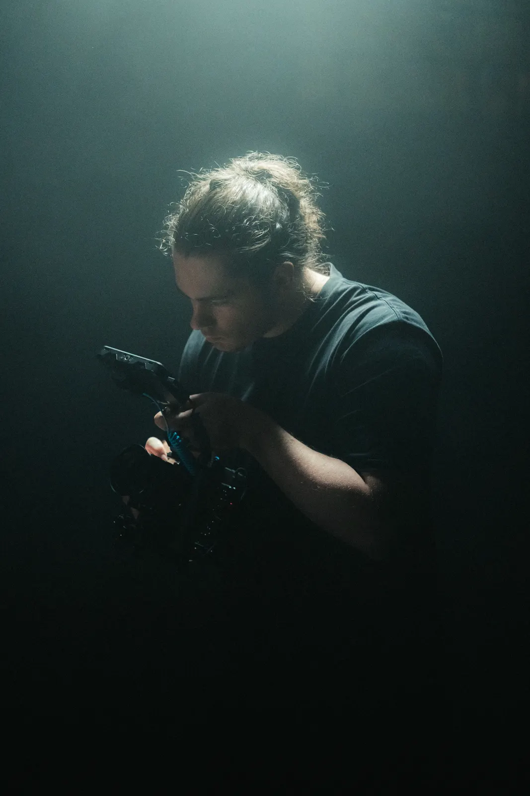Behind-the-scenes portrait of a camera operator in low light.