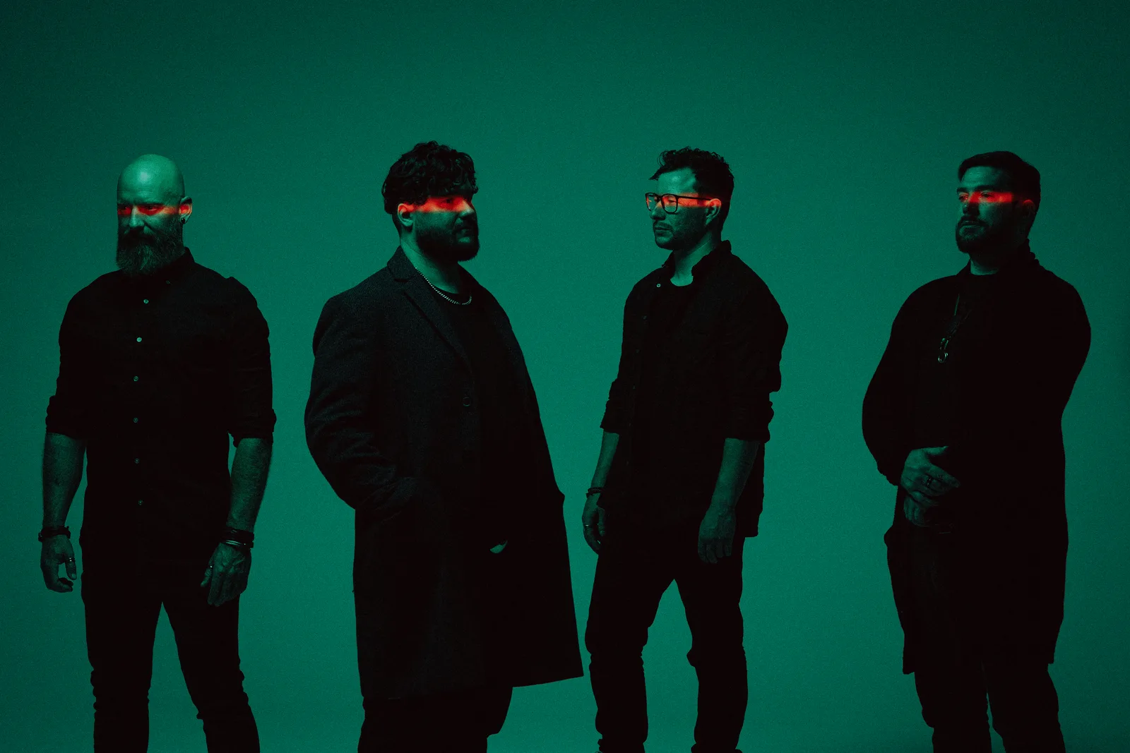 Portrait of a four-piece band in black against a green backdrop.
