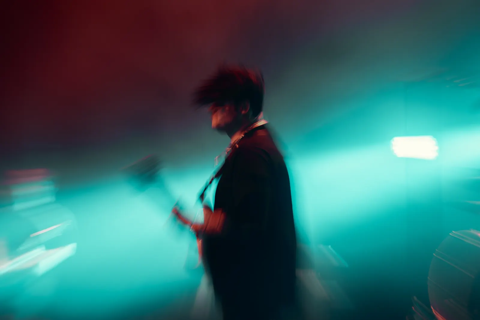 Live music photo with cyan and red light and musician motion blur.