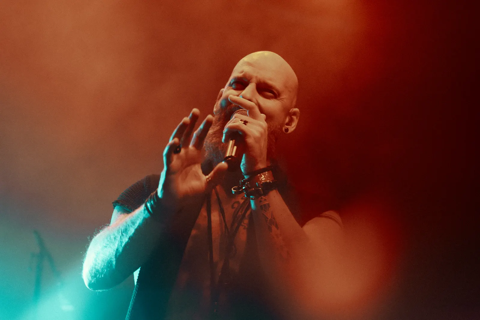 Live music photo of a vocalist in red and cyan stage light.